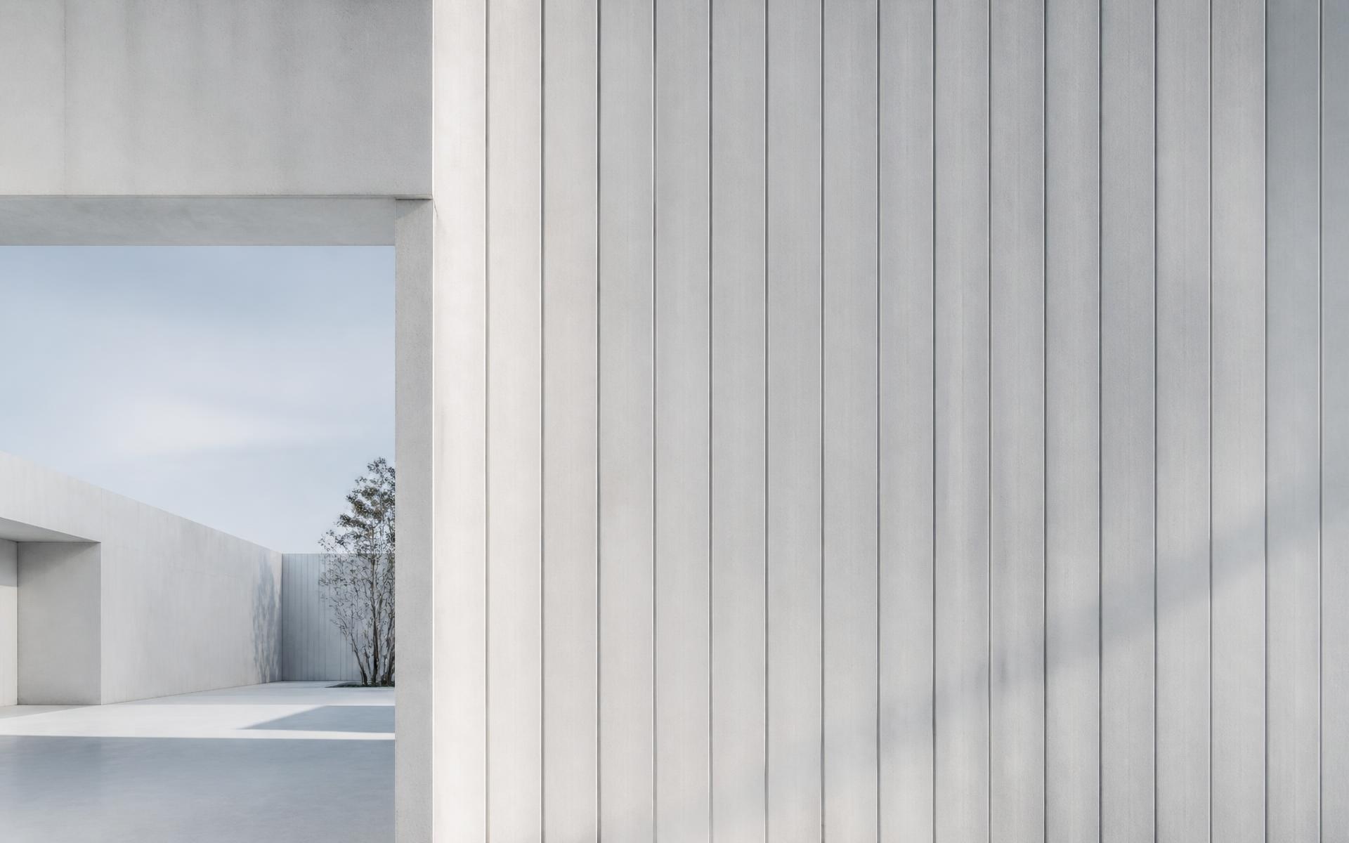 Modernist white concrete facade with fine vertical structure in natural daylight